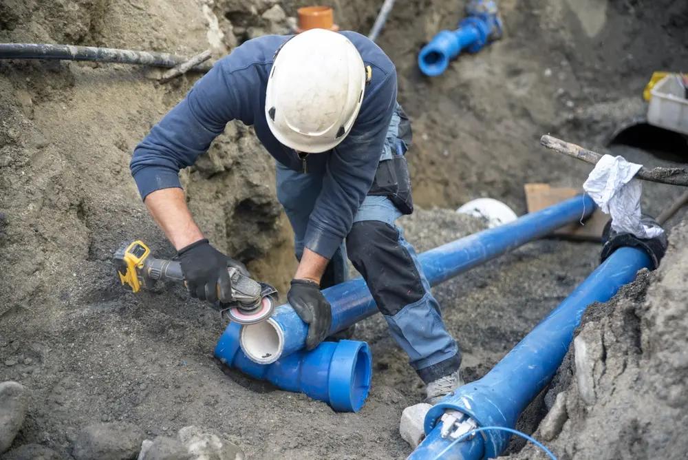 Plumber repairing a burst pipe in a flooded residential basement in Orillia or North Bay