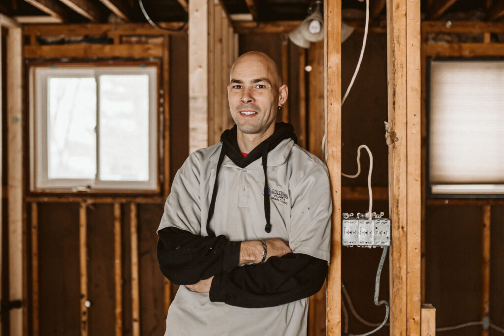 Poly-B Plumbing technician shaking hands with a homeowner in front of a well-maintained home